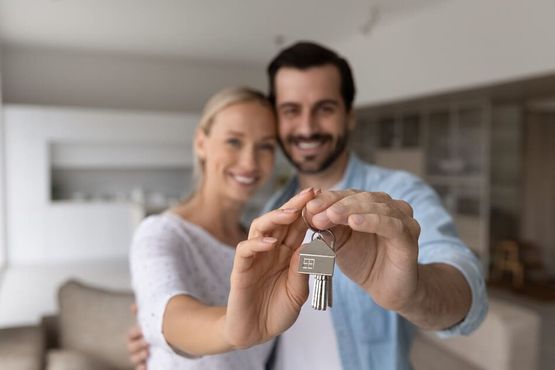 pareja feliz posando con las llaves de una nueva casa